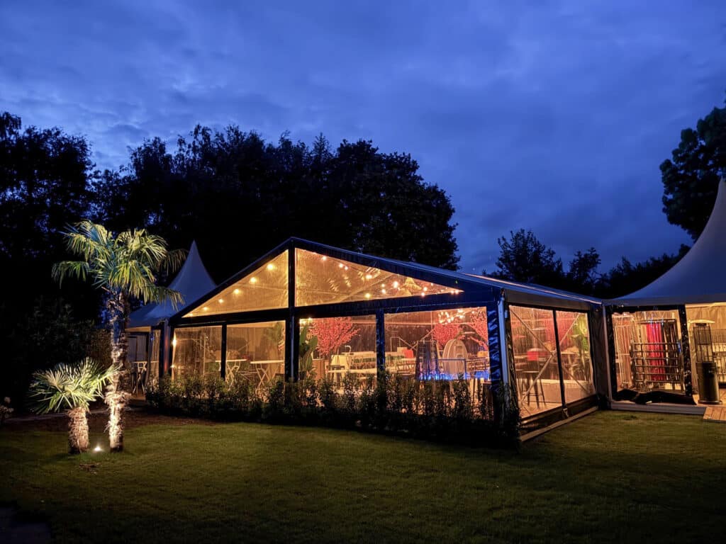 Verlichte transparante aluhal met sfeervolle verlichting in de avond.