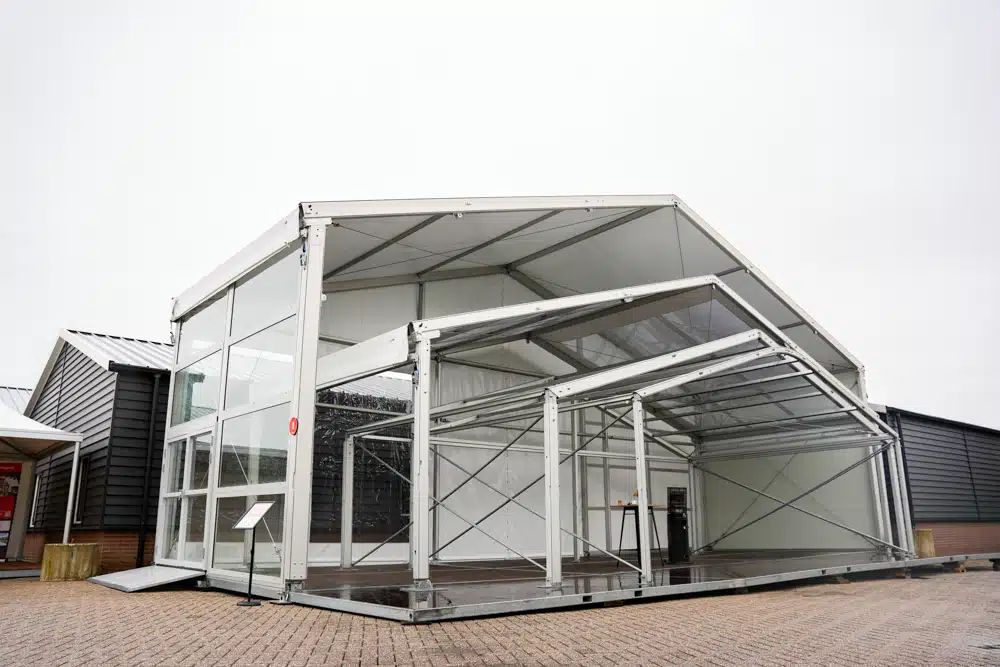 Zijaanzicht van demotent met glaswand en aluminium frame.