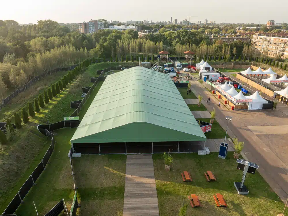 Brede groene booghal geplaatst als festivaltent met zijwanden
