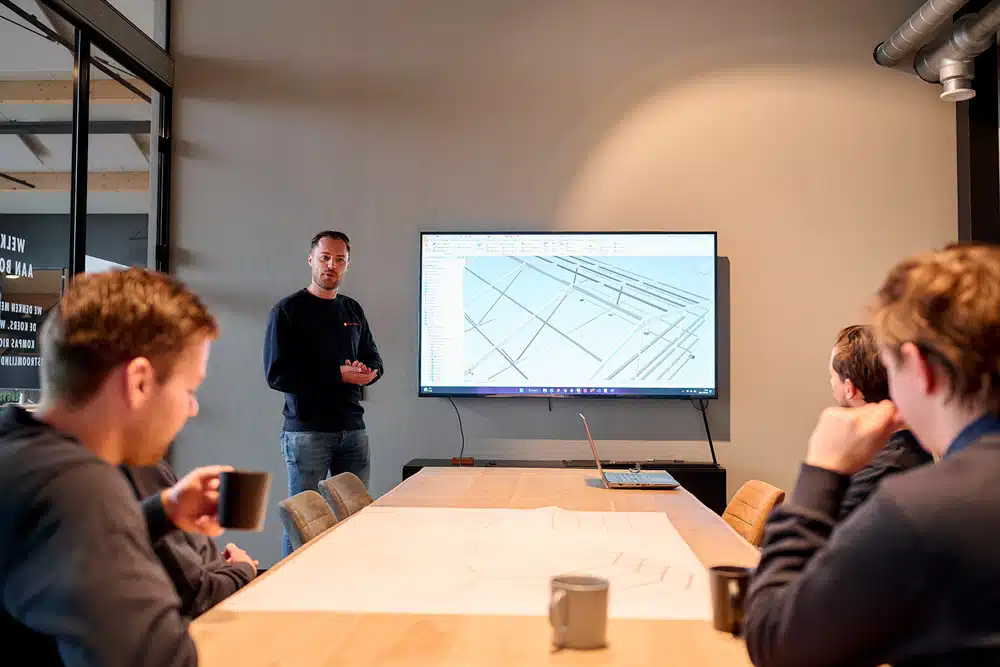 Managergeeft presentatie over 3D-model van aluminium tentconstructie op groot scherm