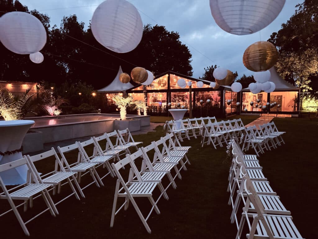 Sfeervolle avondsetting met aluhal en pagodetenten omringd door stoelen en decoratie.