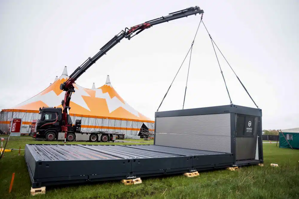 Mobiele unit wordt met kraan geplaatst bij evenementtent